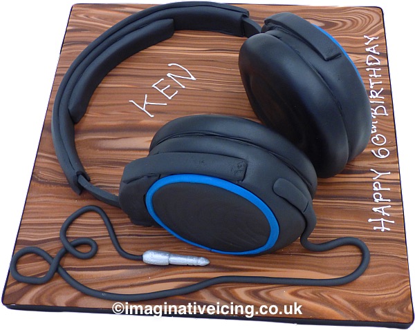 3D headphones birthday cake - the headphones are made of cake with icing 'headband' and lead. board is iced to look like wood with birthday message piped in icing.
